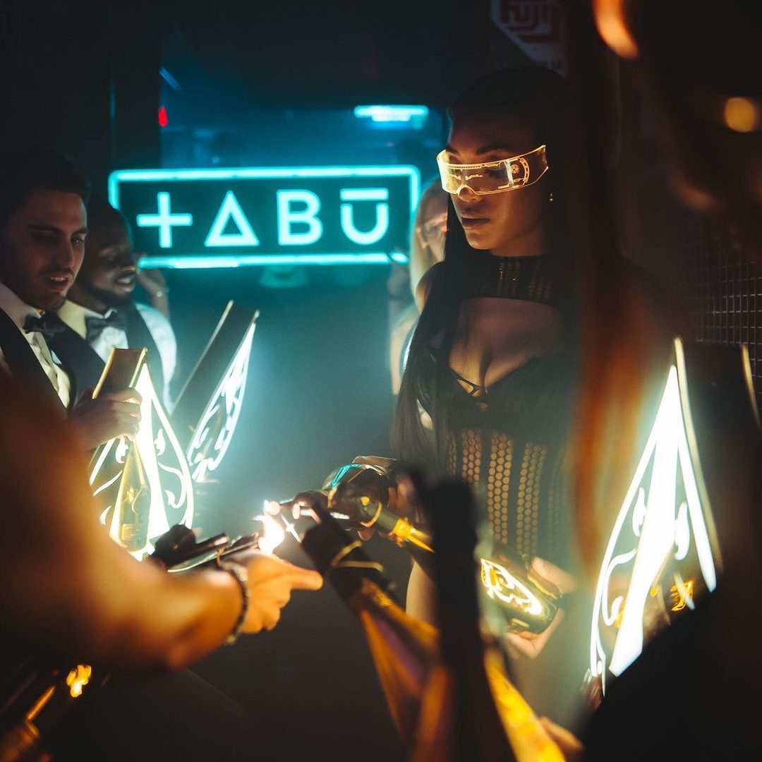 Tabu London champagne show girls lighting up sparklers with the Tabu Logo in the background