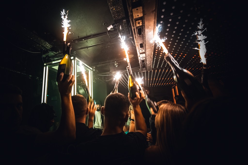 Waiters carrying champagne bottles and sparklers inside a luxury nightclub in Mayfair, London.