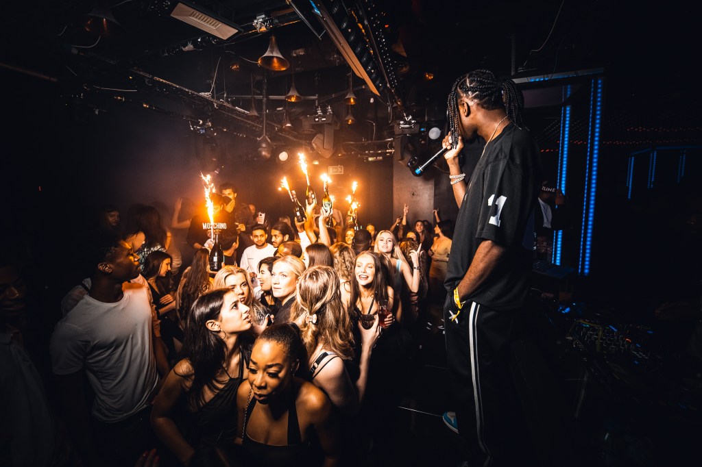Table and guestlist clients dancing in front of the stage with London bottle service running in the background.